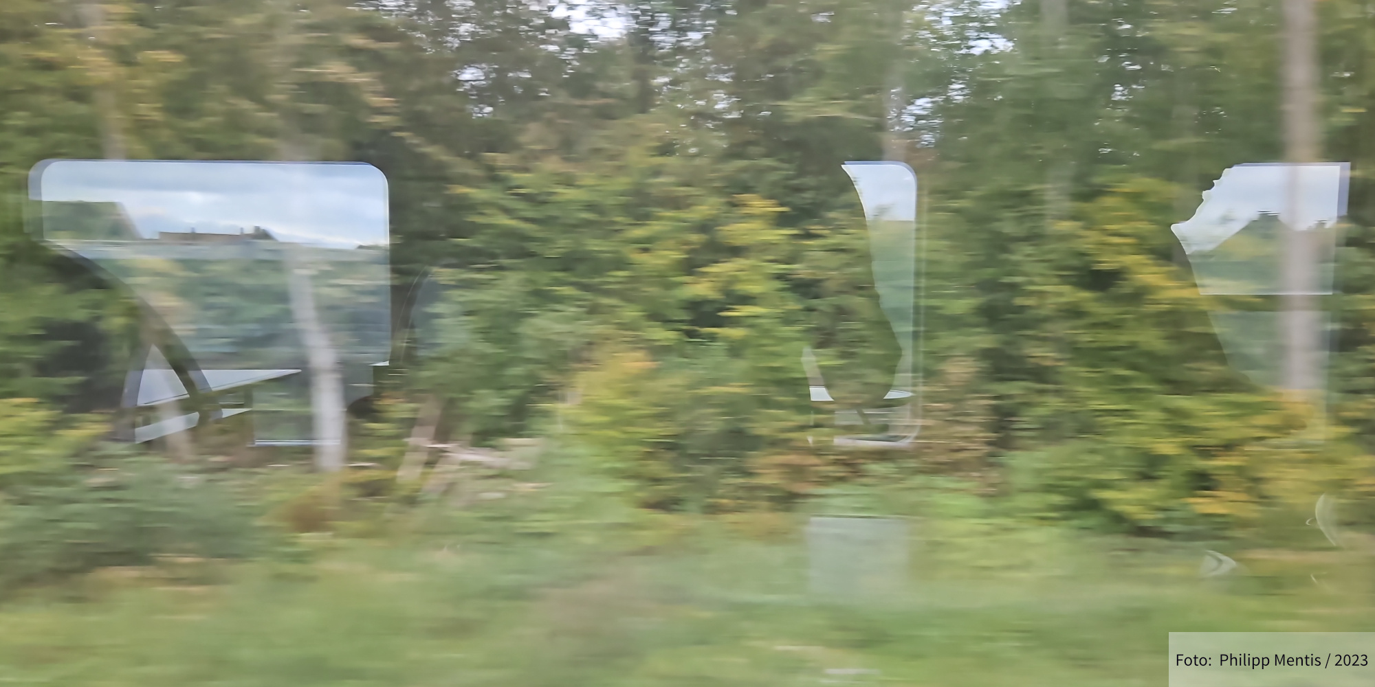 !B Blick aus dem Zugfenster zeigt eine rasende Landschaft.