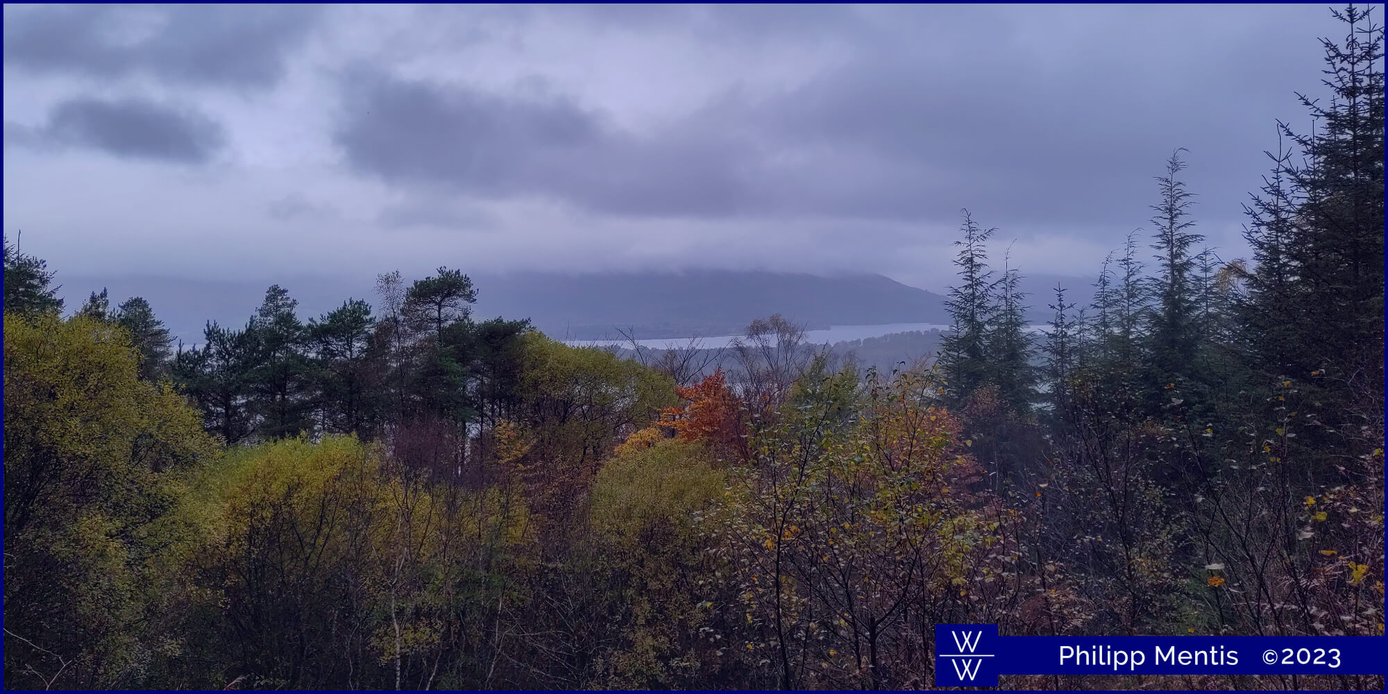 !B View from a hill, where through the trees Loch Lomond can be seen.