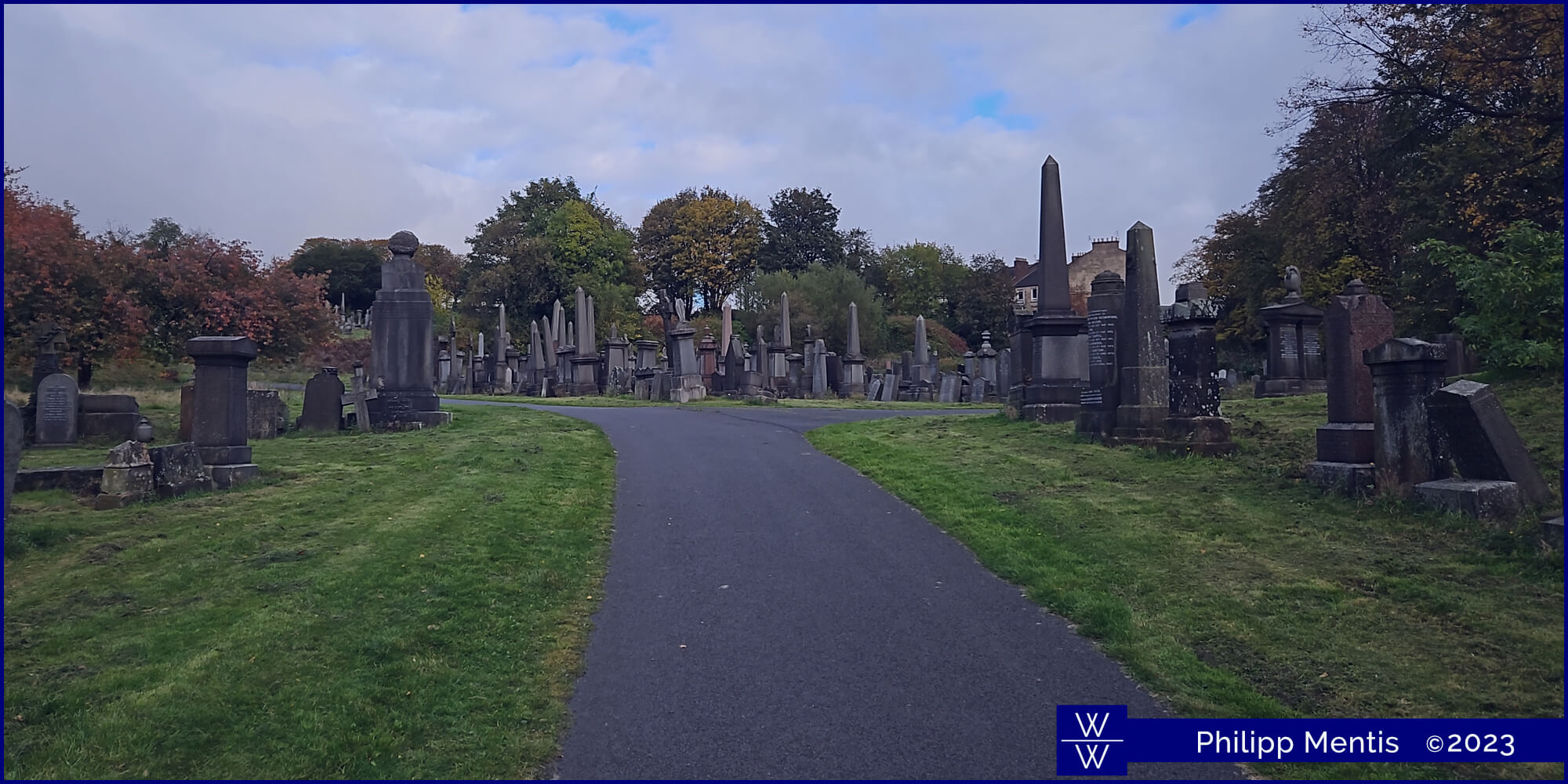 !B Small asphalt road leading into Glasgow necropolis, with gravestones to each side.