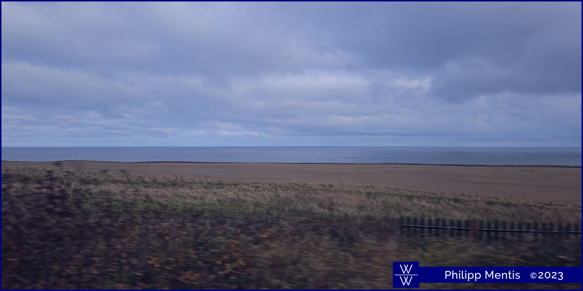 !B The Northern British sea seen from a train window. A narrow beach gliding into the water.