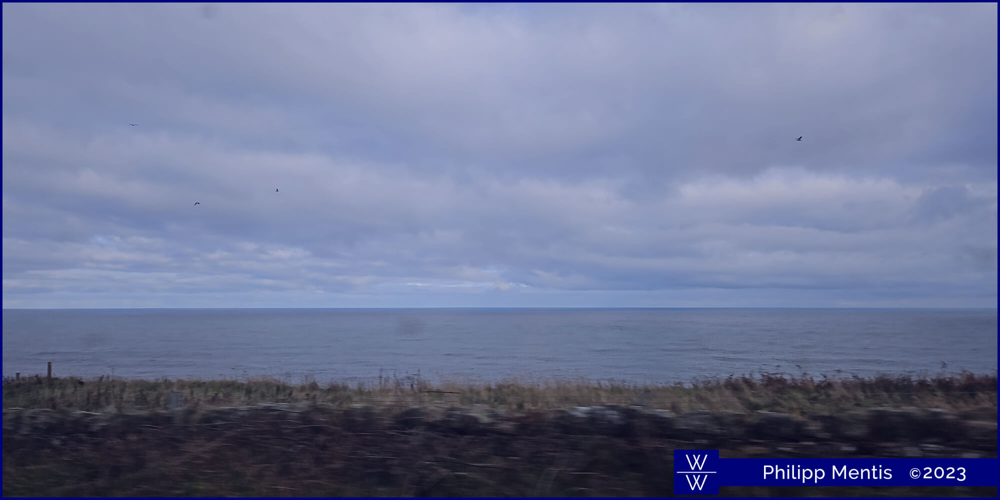 !B Outside the train window, the blueish British sea flows by.